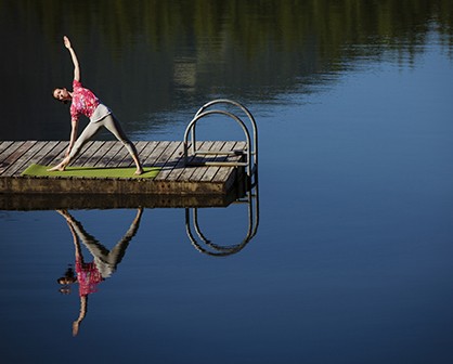 woman doing gymnastics on the dock of a lake
