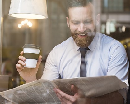 man reading the newspaper over coffee